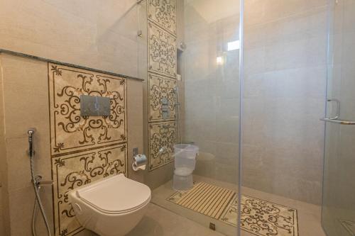 a bathroom with a toilet and a glass shower door at Trideus The Wild Fraser Corbett in Rāmnagar