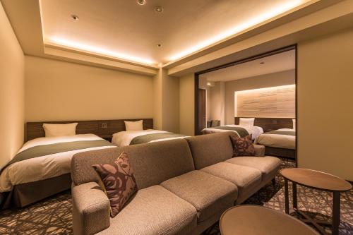 a room with two beds and a couch and a mirror at Hotel Grand Vert Kyu Karuizawa in Karuizawa