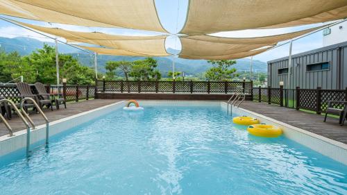 a swimming pool with an umbrella and some chairs at Gapyeong Dangdangi Pet Poolvilla Blue in Gapyeong