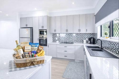 a kitchen with white cabinets and a basket of food at 4BR Family Home w Golf Course Views, BBQ & Secure Parking in Rosslea