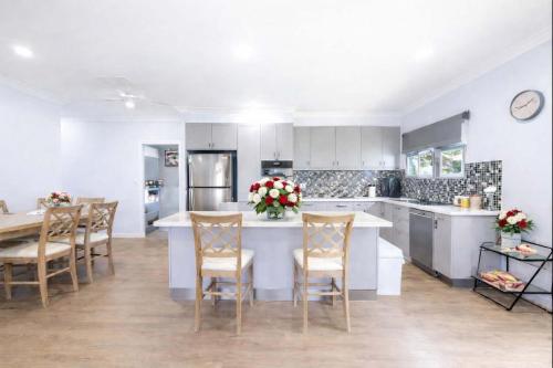 a kitchen with white cabinets and a table and chairs at 4BR Family Home w Golf Course Views, BBQ & Secure Parking in Rosslea