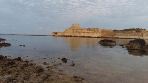 a view of a body of water with some rocks at Marsalforn Apartment Del Mar in Marsalforn