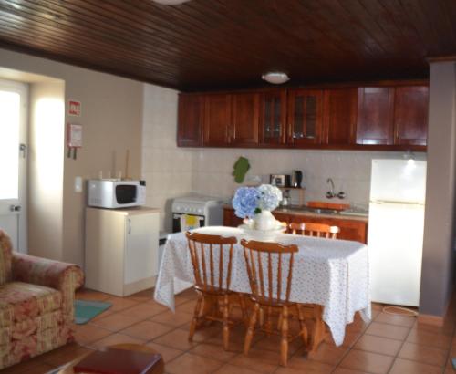 a kitchen with a table with chairs and a refrigerator at TINA 3B - Alojamento Local - RRAL 760 in Porto Martins