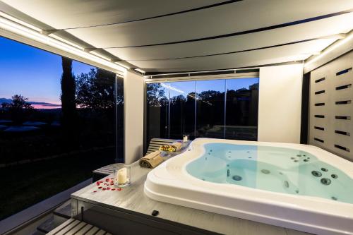 una vasca da bagno in una stanza con una grande finestra di Il Melograno Agriturismo & SPA a Pianello