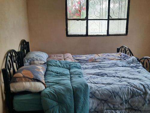 an unmade bed in a bedroom with a window at استراحة الباشا albash farm stay in Al Karāmah