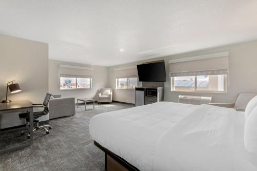 a hotel room with a large white bed and a desk at Clarion Pointe Prescott Valley in Prescott Valley