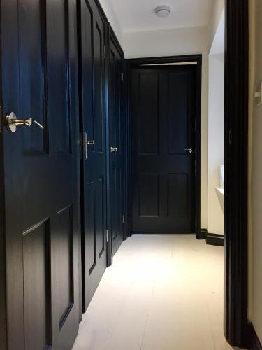 a hallway with black doors and a white floor at Book Heaven in Bridport