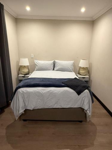 a bedroom with a large bed with two lamps at Avo 2 on 27 Drew in Howick