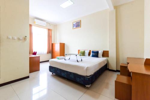 a bedroom with a bed and a desk at Urbanview Hotel Bartu Moh Toha Bandung by RedDoorz in Bandung