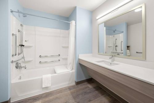 a bathroom with a tub and a sink and a mirror at WoodSpring Suites Medford near I-5 in Medford