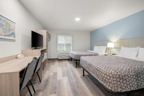 a room with two beds and a desk and a television at WoodSpring Suites Medford near I-5 in Medford