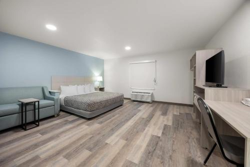 a room with a bed and a couch and a television at WoodSpring Suites Medford near I-5 in Medford