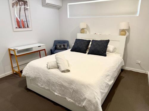 a bedroom with a white bed and a blue chair at Coastal Retreat in Scarborough in Perth