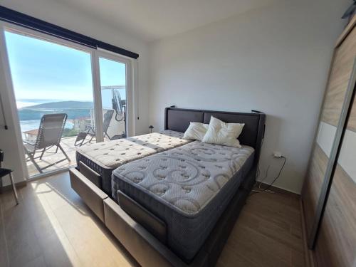 a bedroom with a large bed and a large window at Exclusive penthouse with stunning panoramic views in Prijevor