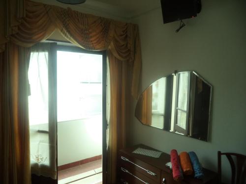 a bedroom with a mirror and a dresser and a window at Casa Romão in Nazaré