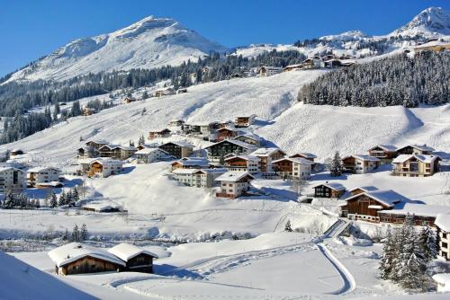 a village covered in snow with a mountain in the background at Chalet Schneekristall in Lech am Arlberg