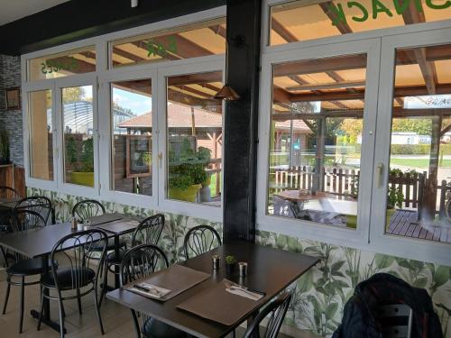 a restaurant with tables and chairs and windows at Camping les Marguerites in Gamaches