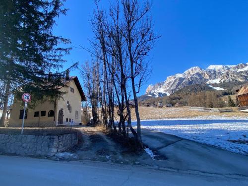 a building on the side of a road with snowy mountains at Ca' Il Guscio in Cortina dʼAmpezzo