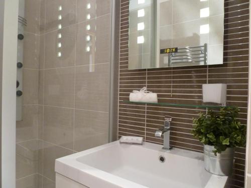 een badkamer met een witte wastafel en een spiegel bij LES TROIS CHANDELIERS un petit paradis en plein centre ville in Bordeaux