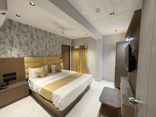 a bedroom with a large bed and a television at Hotel Pine Lake in Ahmedabad