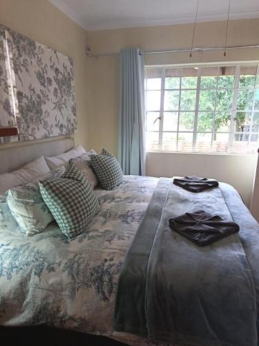 a bedroom with a bed with pillows and a window at Uitkyk Guest House in Fouriesburg