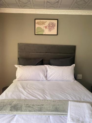 a bed with white sheets and a picture on the wall at Namhla Guest House in Nongoma