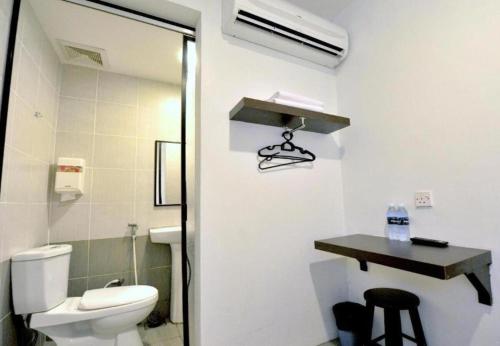 a bathroom with a toilet and a sink and a table at Point Stay BDC Airport in Kuching