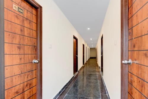 a corridor with wooden doors and white walls at Hotel O RB STAY in Haidar Sāhibgūda