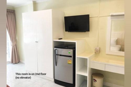 a room with a refrigerator and a tv on a wall at Thai Orchid Guest House in Jomtien Beach