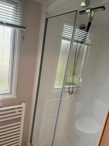 a glass shower door in a bathroom with a window at S & S Retreat in Heysham