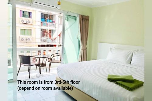 a bedroom with a bed and a table and a balcony at Thai Orchid Guest House in Jomtien Beach