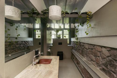 a bathroom with a sink and a stone wall at Malhar - Your Home Beneath The Clouds in Sultan Bathery