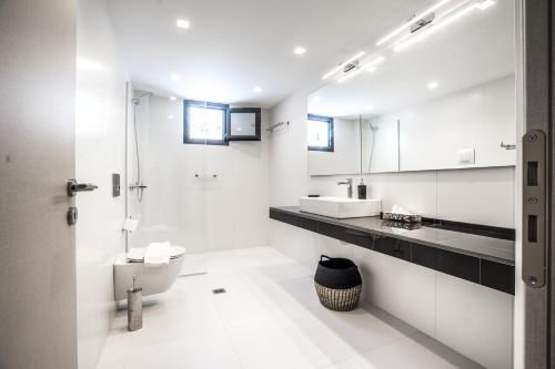 a white bathroom with a toilet and a sink at Villa Daniela & Apartments in Koutsounari