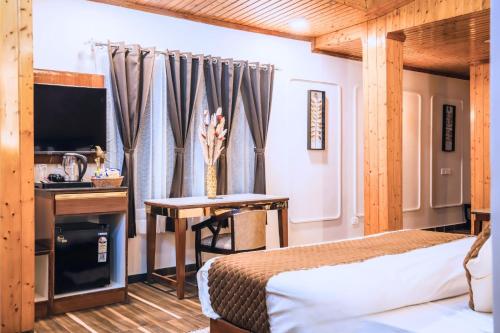 a bedroom with a bed and a desk and a television at Sunoraa Luxury Hotel & Spa in Mussoorie