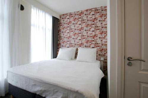 
a bedroom with a white bed and white walls at De With Studio's in Rotterdam
