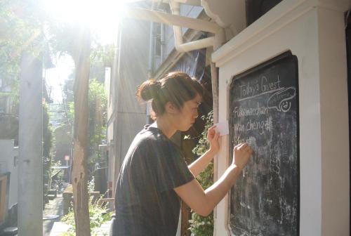 a woman is standing next to a chalkboard at Guest House FUTARENO in Yokohama