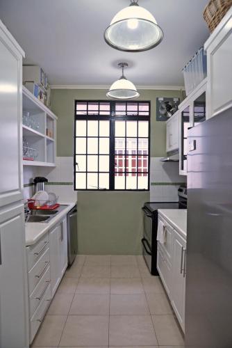 a kitchen with white cabinets and a window at Culture Crossroads Inn in Port-of-Spain