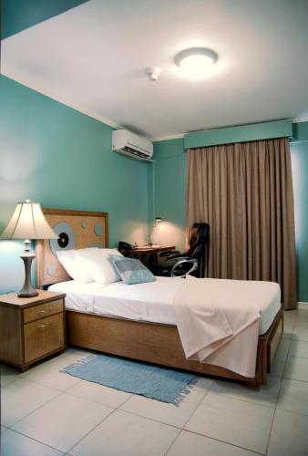 a bedroom with a bed and a desk with a lamp at Culture Crossroads Inn in Port-of-Spain