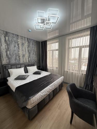 a bedroom with a bed and a chair and windows at Gyumri Moderna in Gyumri