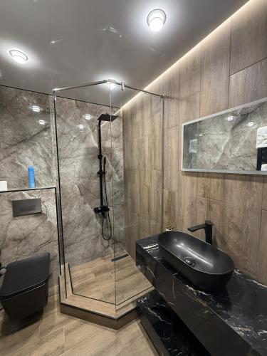 a bathroom with a glass shower and a black sink at Gyumri Moderna in Gyumri