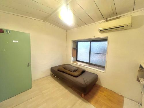 a room with a bed in a room with a window at Bridgeブリッジゲストハウス in Shimonoseki