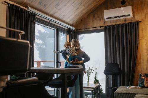 a woman holding a child standing in front of a window at Domek Jak z Obrazka in Sierpnica