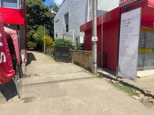 an empty street in front of a red building at Cattleya Guest House in Tissamaharama