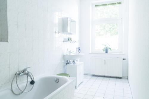 uma casa de banho branca com uma banheira e um lavatório em Unterkunft Leipzig em Leipzig