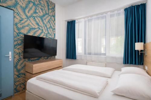a bedroom with two beds and a flat screen tv at WOW City Hostel in Budapest