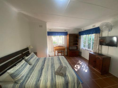 a bedroom with a large bed and a television at Fishermans Cottage - BillsBest in Port Edward