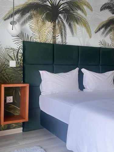 a bed with white pillows and a green headboard at White Guest in Fátima
