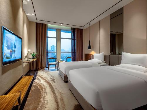 a hotel room with three beds and a flat screen tv at 半山酒店 in Kaili