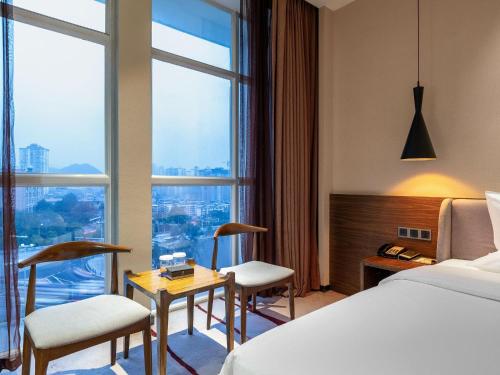 a hotel room with a bed and two chairs and a table at 半山酒店 in Kaili