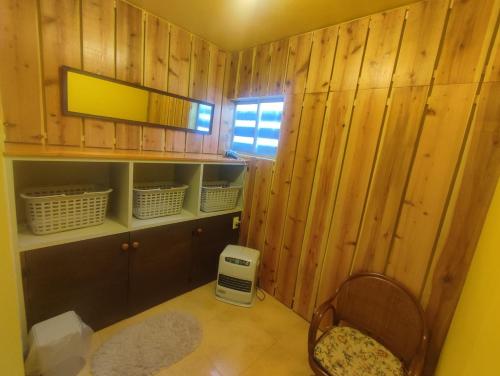 a room with wooden walls and a chair and a mirror at PEUF Lodge in Otari